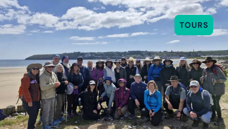 Celtic Ways group of hikers posing together on a coastal trail with the sea and cliffs in the background.