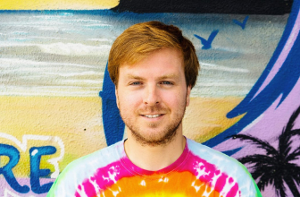 Portrait of a surf school staff member standing in front of a beach mural.