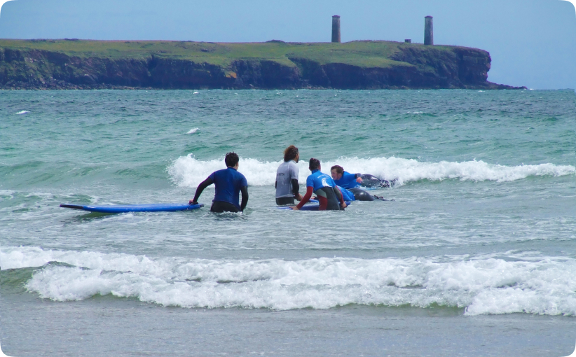 Group of surfers practicing in shallow water with instructors during a family lesson.