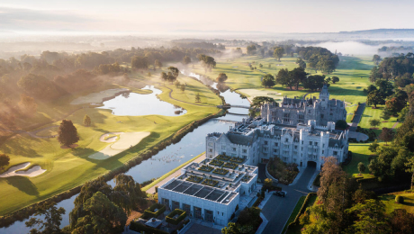 Aerial view of Limerick castle beside a river and golf course, surrounded by landscaped grounds and countryside.