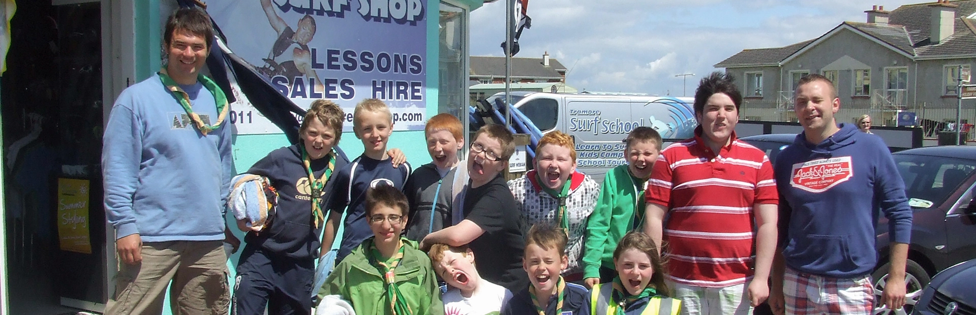Youth group posing outside Tramore Surf Shop with leaders before a surf activity.