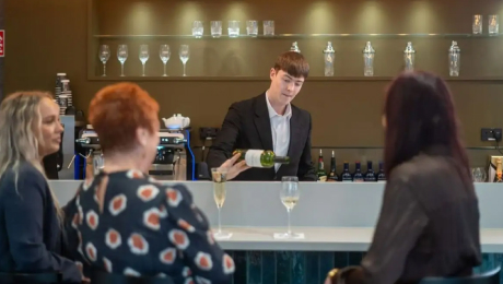 Bartender pouring wine for guests seated at a counter inside House of Waterford Café