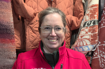 Portrait of a smiling surf shop staff member wearing a red jacket indoors.