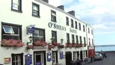 Exterior of O’Shea’s Hotel with flower boxes beneath the windows, located near the seafront.