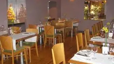 Dining room with set tables, wooden chairs, and neatly arranged place settings inside The Tannery Restaurant