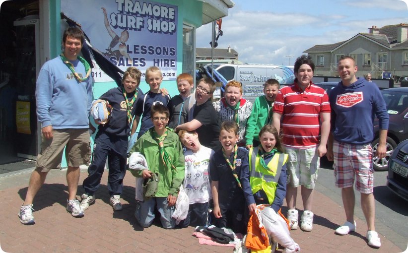 Youth group posing outside Tramore Surf Shop with leaders before a surf activity.