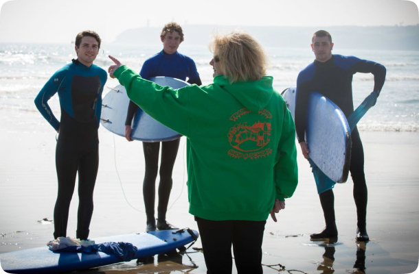 Surf instructor giving directions to students holding boards on the beach before a lesson.